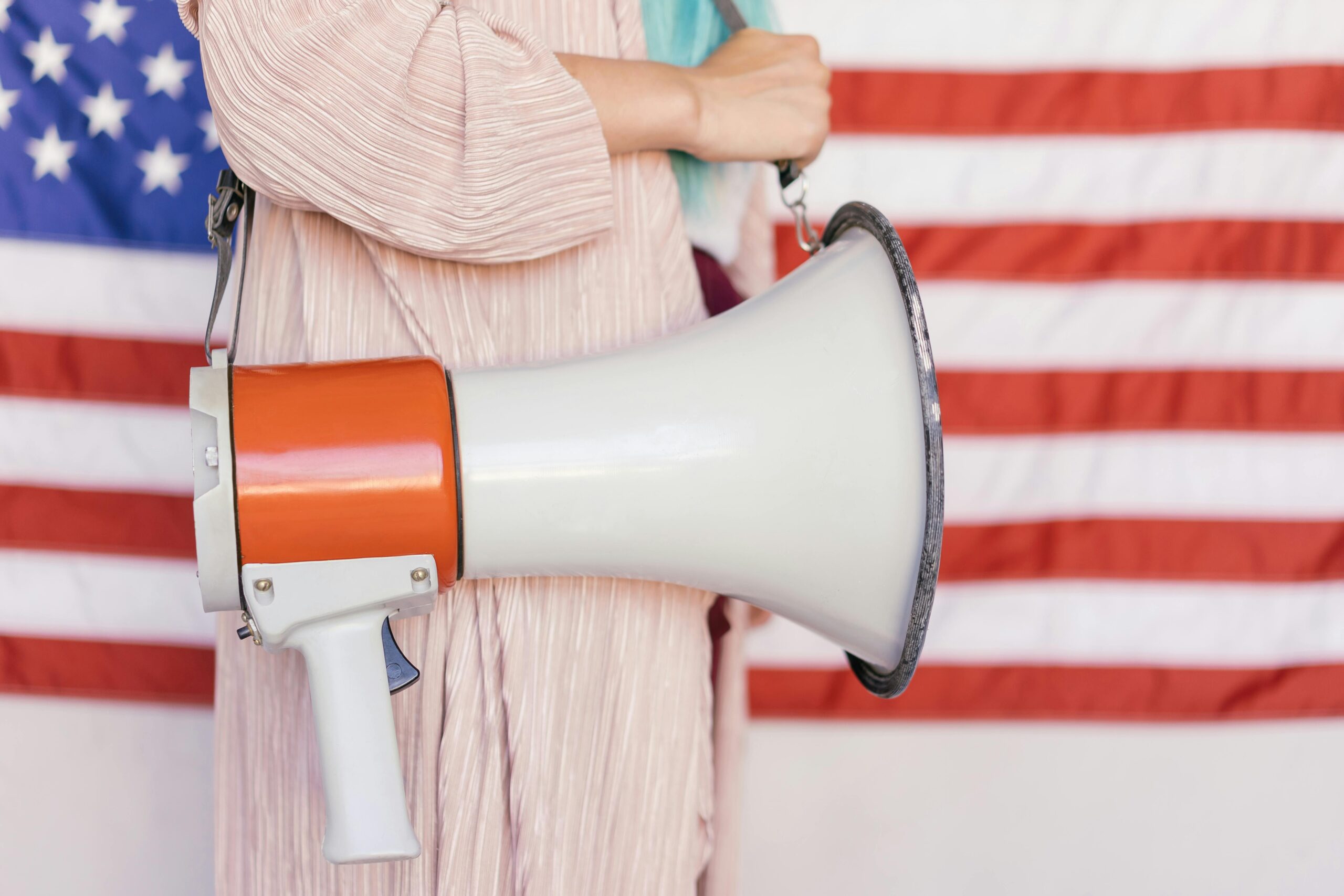 A person holding a megaphone in front of an American flag, symbolizing protest.